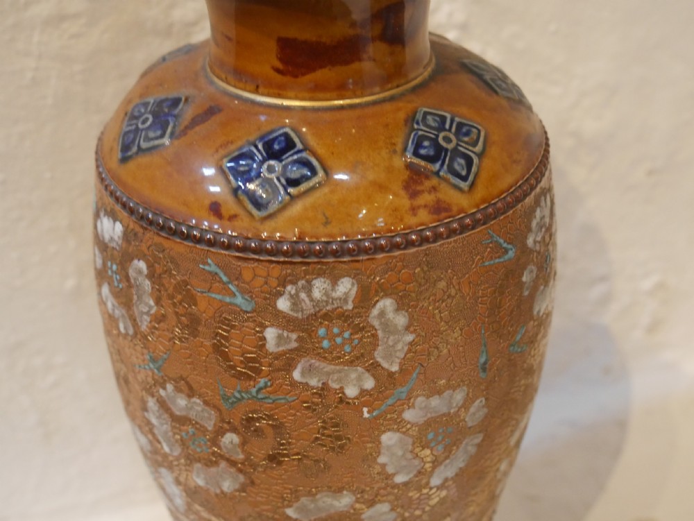 A pair of antique Royal Doulton stoneware vases featuring caramel brown glazing, white floral decorations, and blue foliate accents around the base. View VI