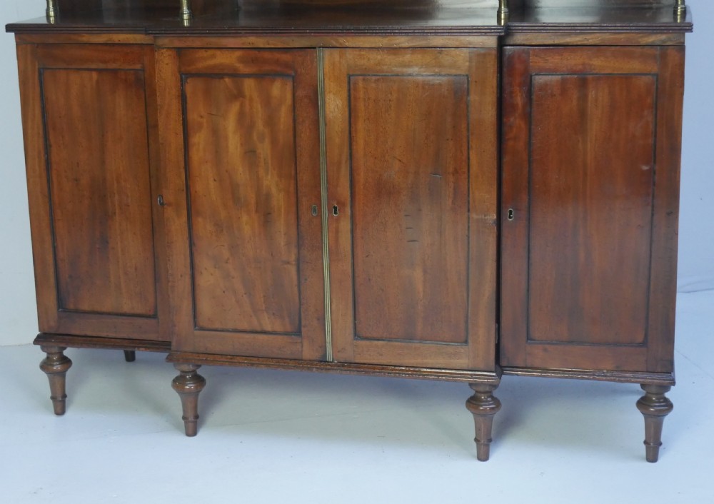 A Georgian mahogany chiffonier featuring an upper display shelf supported by brass columns above panelled cupboard doors and turned legs. View II