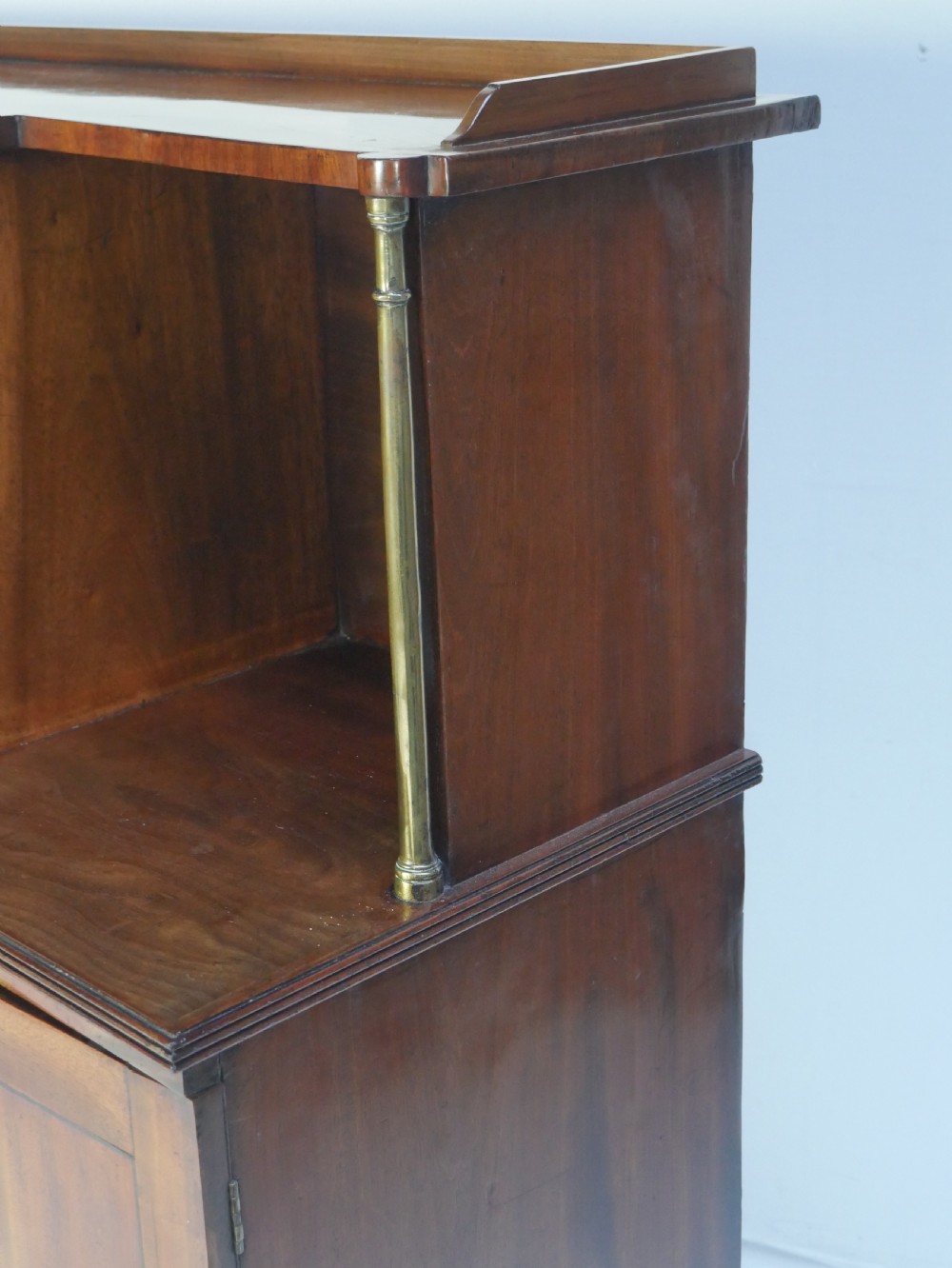 A Georgian mahogany chiffonier featuring an upper display shelf supported by brass columns above panelled cupboard doors and turned legs. View V