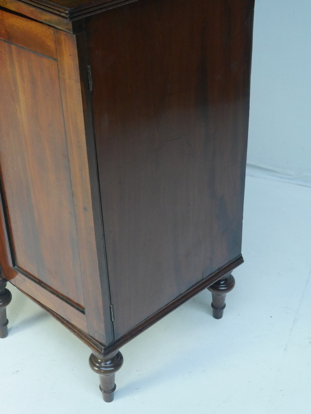 A Georgian mahogany chiffonier featuring an upper display shelf supported by brass columns above panelled cupboard doors and turned legs. View VI