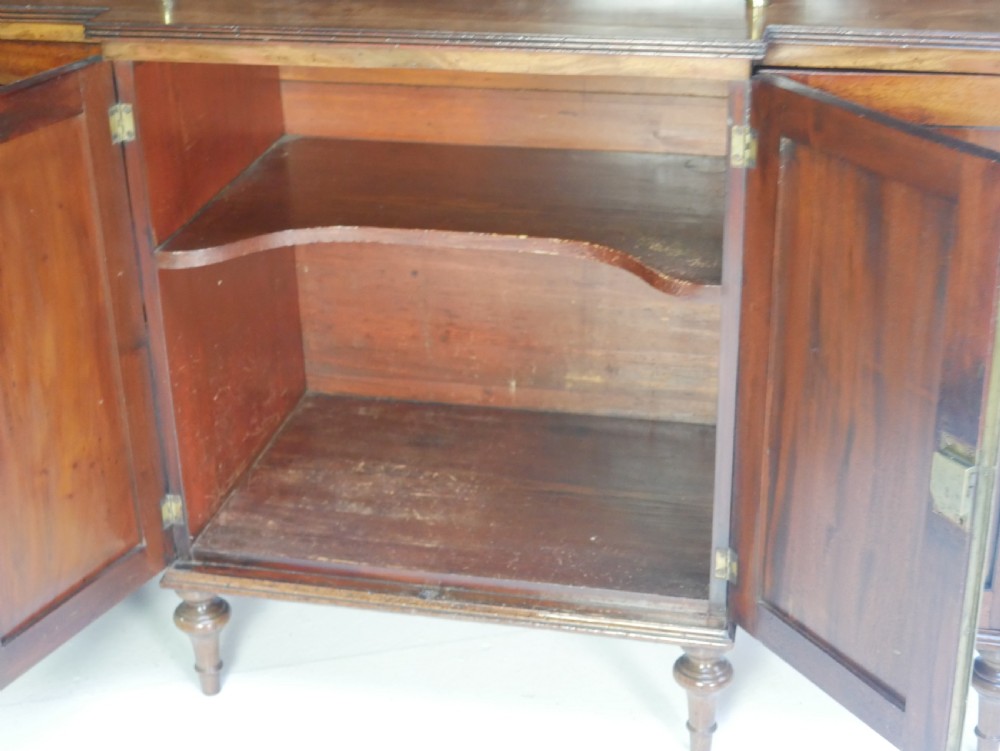 A Georgian mahogany chiffonier featuring an upper display shelf supported by brass columns above panelled cupboard doors and turned legs. View IX