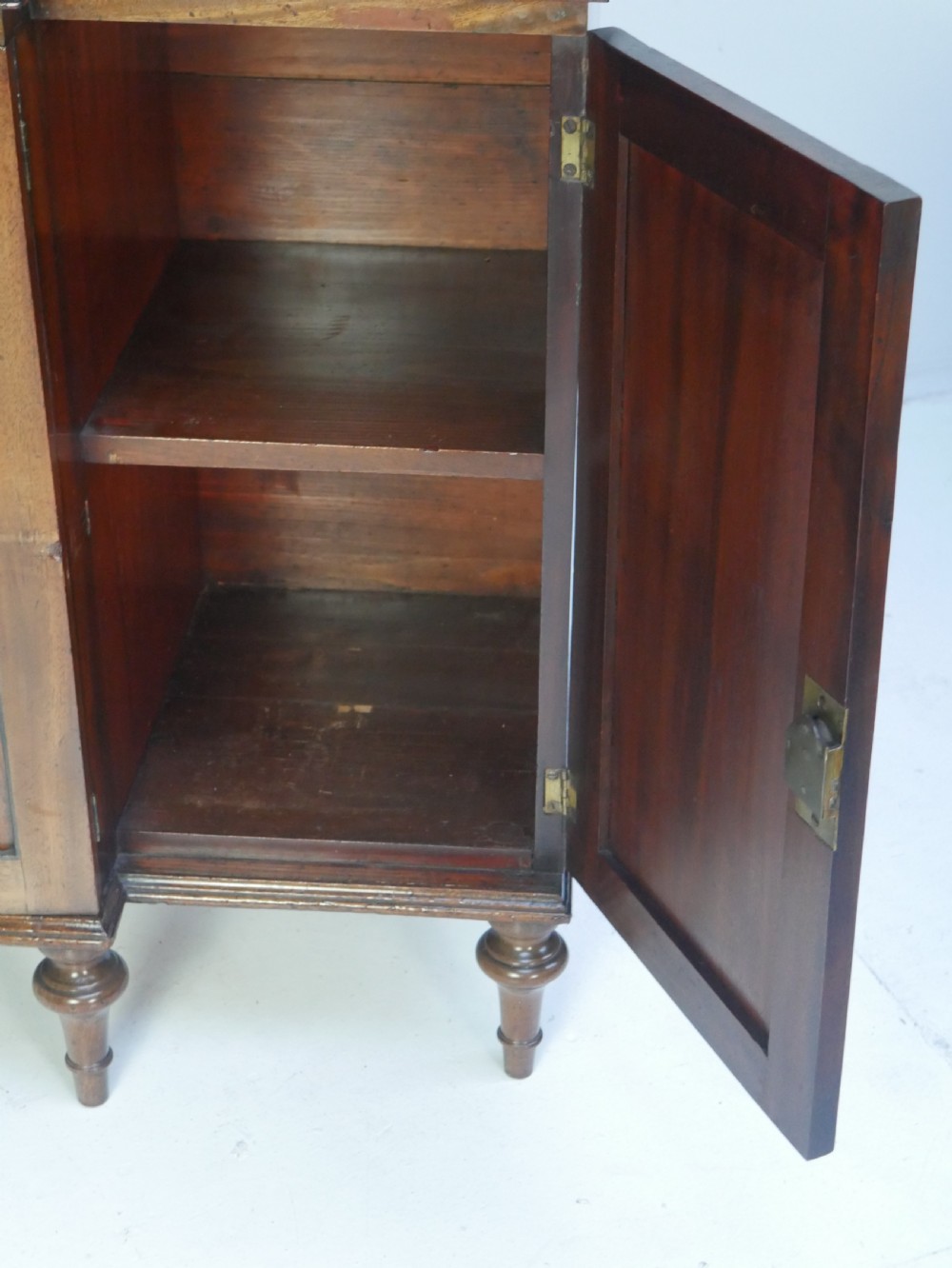 A Georgian mahogany chiffonier featuring an upper display shelf supported by brass columns above panelled cupboard doors and turned legs. View X
