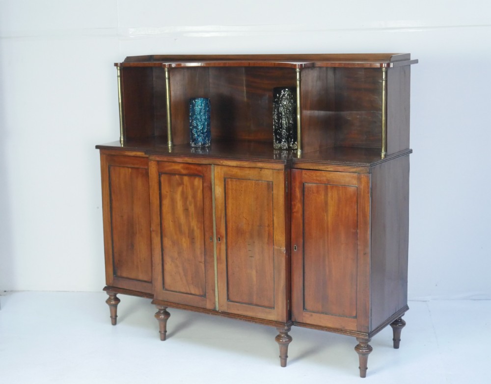 A Georgian mahogany chiffonier featuring an upper display shelf supported by brass columns above panelled cupboard doors and turned legs. View XIII