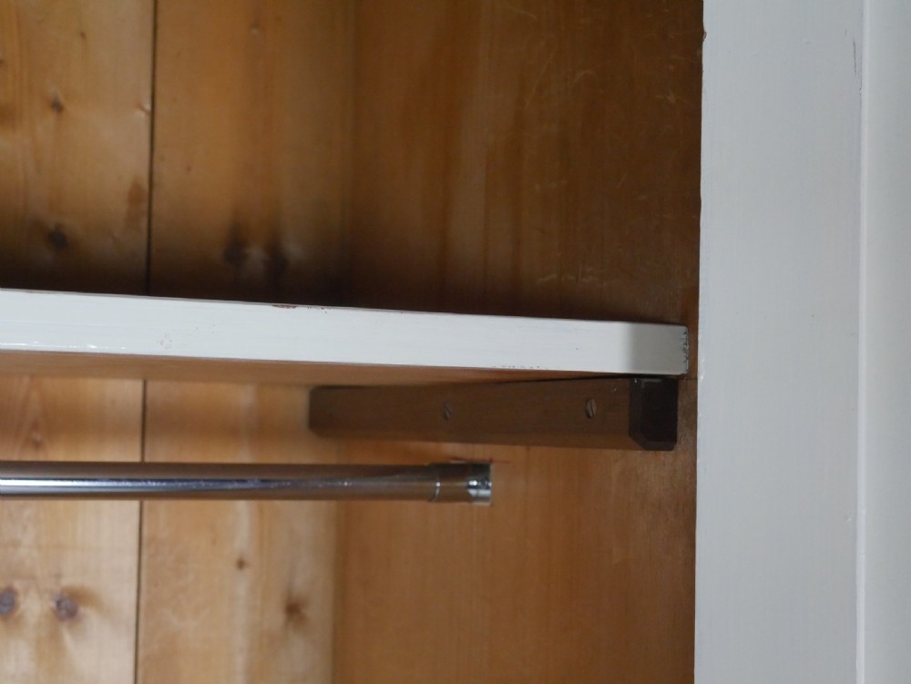 A large double-door white painted wooden wardrobe with open doors revealing a natural pine interior featuring a hanging rail and top shelf. View III