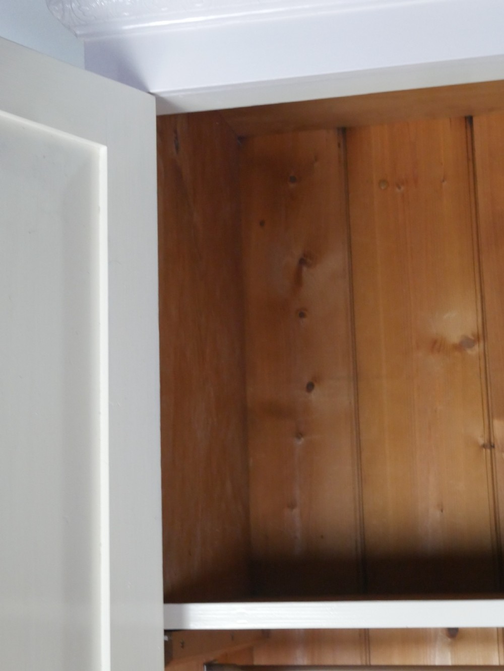 A large double-door white painted wooden wardrobe with open doors revealing a natural pine interior featuring a hanging rail and top shelf. View V