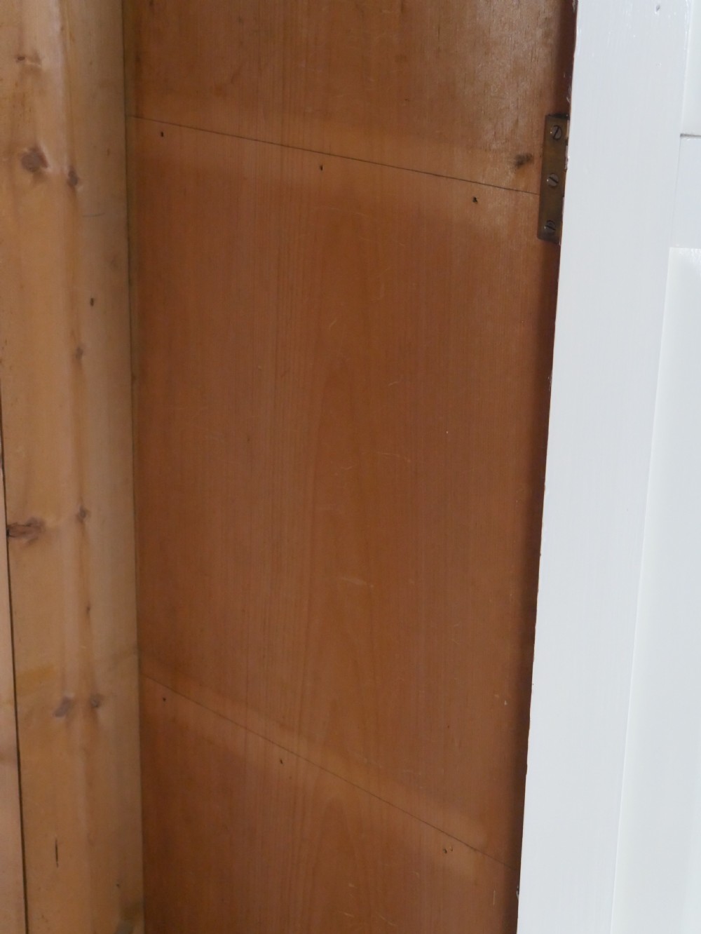 A large double-door white painted wooden wardrobe with open doors revealing a natural pine interior featuring a hanging rail and top shelf. View X