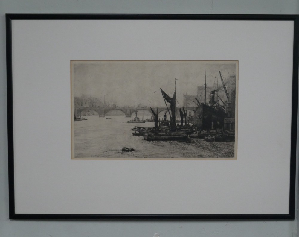 A framed monochrome etching depicting ships and barges on the River Thames with London Bridge in the background.