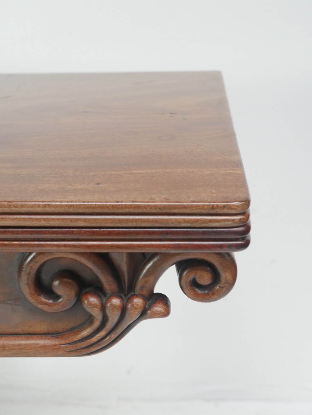 A nineteenth-century mahogany turn-over table with a pedestal stem, carved scroll brackets, and a quadform base on scroll feet. View II