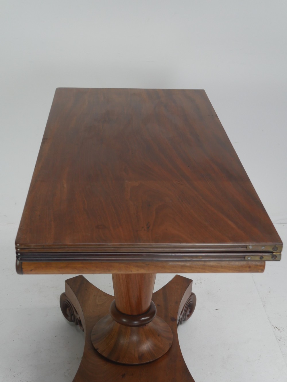 A nineteenth-century mahogany turn-over table with a pedestal stem, carved scroll brackets, and a quadform base on scroll feet. View VIII