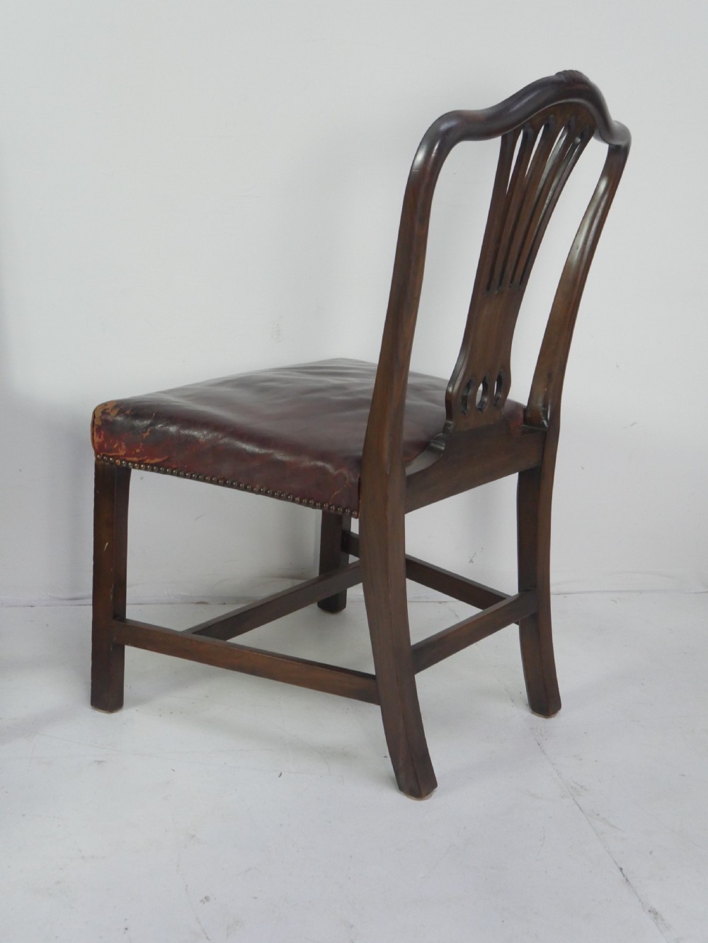 A set of eight mahogany Chippendale style dining chairs featuring pierced splat backs, square legs with stretchers, and burgundy leather seats trimmed with brass studs. View VIII