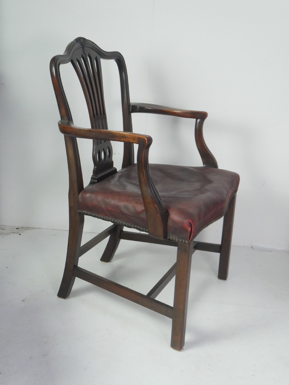 A set of eight mahogany Chippendale style dining chairs featuring pierced splat backs, square legs with stretchers, and burgundy leather seats trimmed with brass studs. View XI