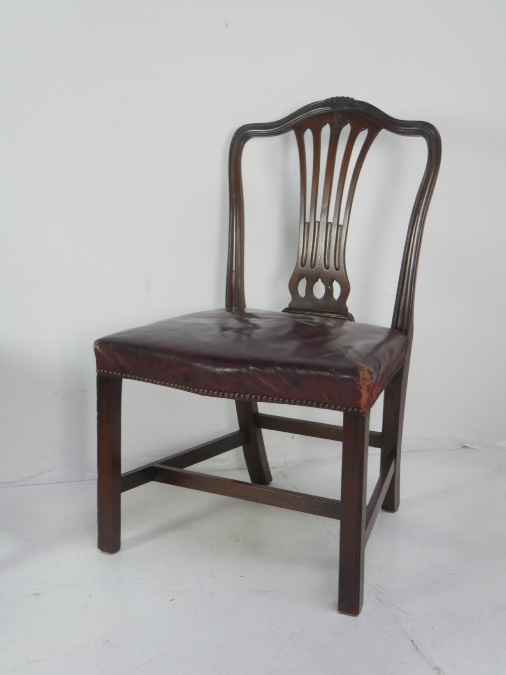 A set of eight mahogany Chippendale style dining chairs featuring pierced splat backs, square legs with stretchers, and burgundy leather seats trimmed with brass studs. View III
