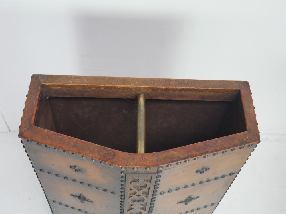 A tall, angular brown leather umbrella stand crafted with studded metal borders and decorative embossed detailing. View II