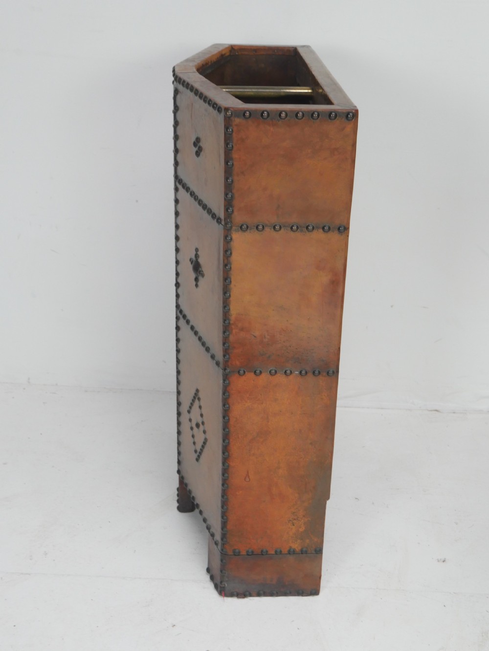 A tall, angular brown leather umbrella stand crafted with studded metal borders and decorative embossed detailing. View VI