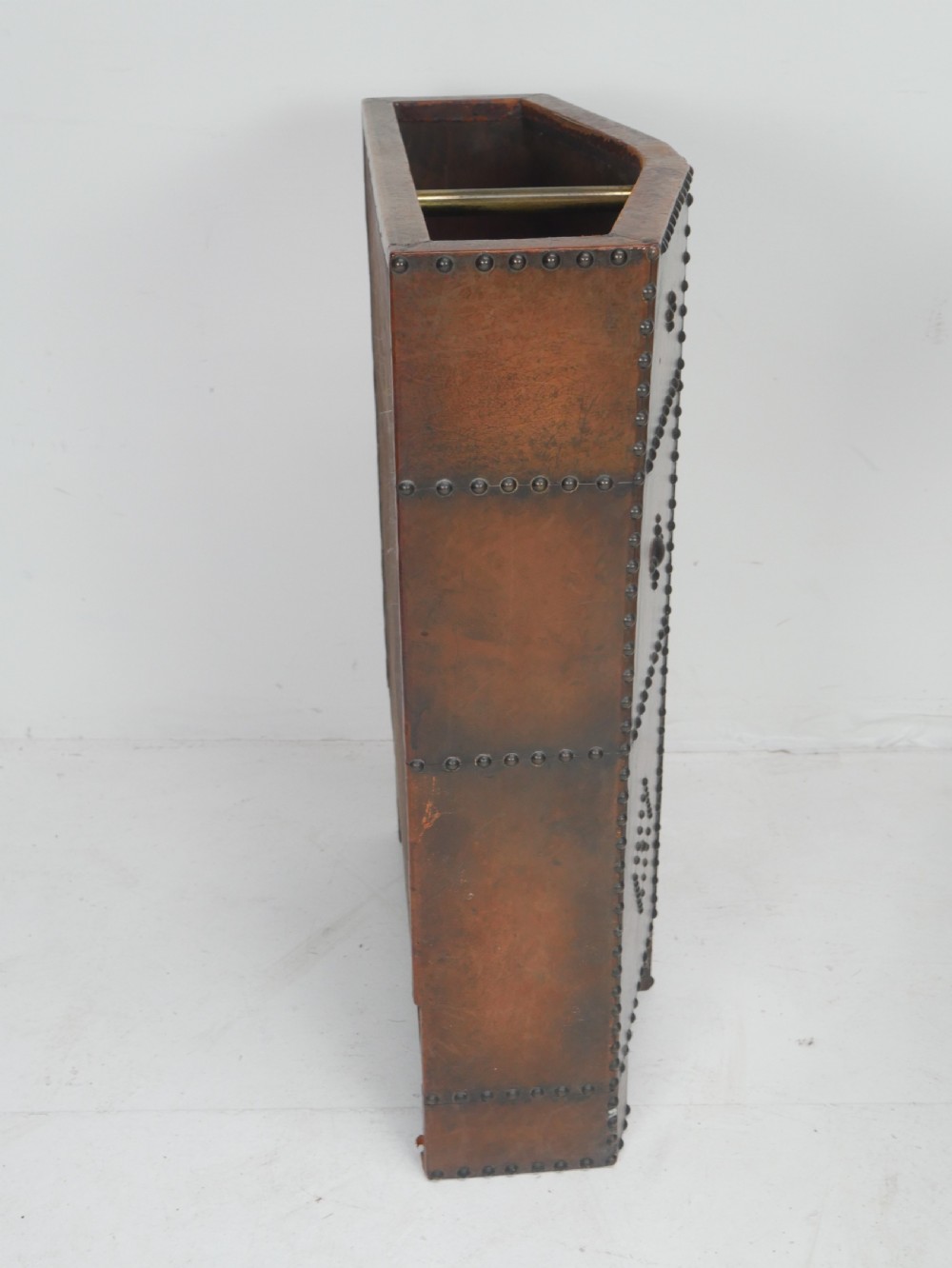 A tall, angular brown leather umbrella stand crafted with studded metal borders and decorative embossed detailing. View VIII