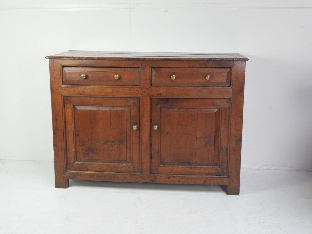 A Georgian oak dresser base featuring two top drawers above two fielded panel cupboard doors fitted with small brass knobs.