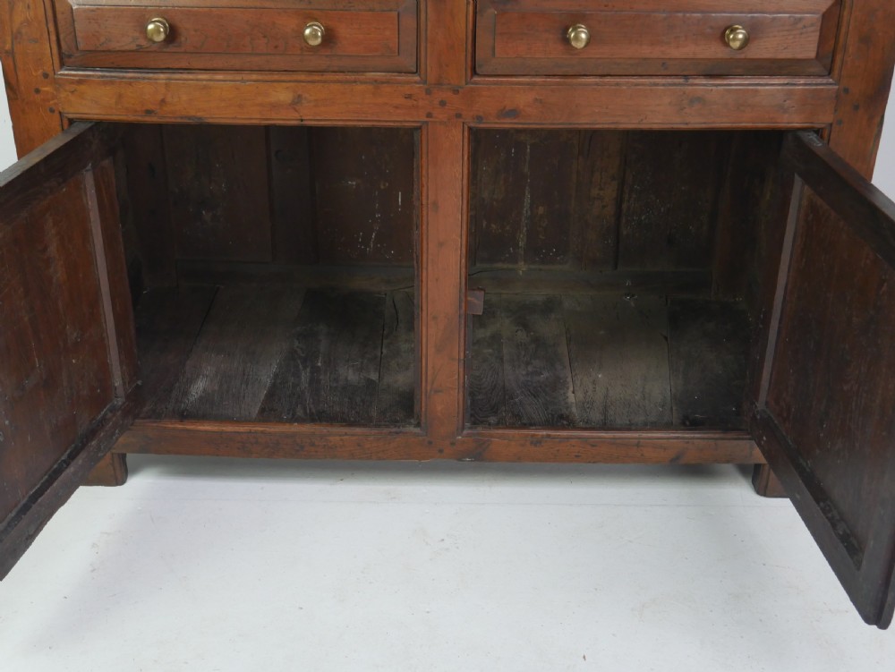 A Georgian oak dresser base featuring two top drawers above two fielded panel cupboard doors fitted with small brass knobs. View VII