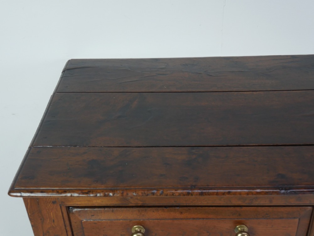 A Georgian oak dresser base featuring two top drawers above two fielded panel cupboard doors fitted with small brass knobs. View VIII