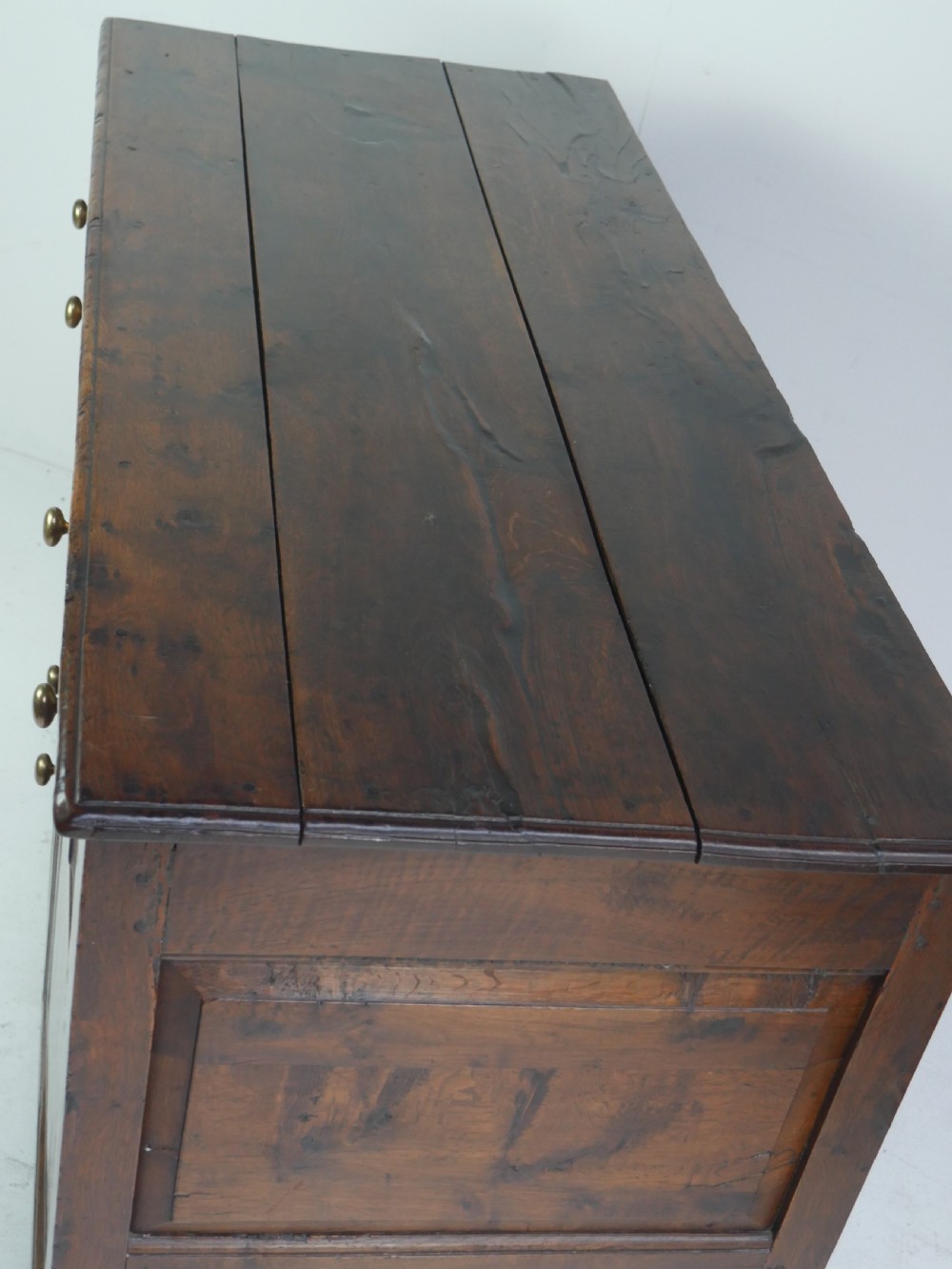 A Georgian oak dresser base featuring two top drawers above two fielded panel cupboard doors fitted with small brass knobs. View XIV