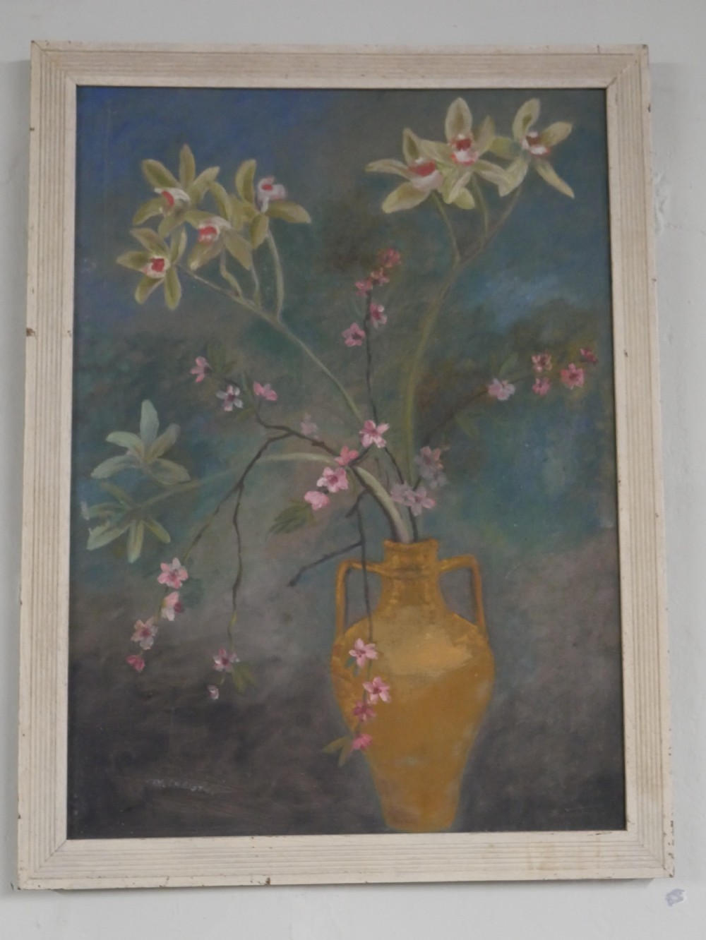 A 1960s framed floral still life painting depicting green orchids and pink blossoms in a yellow two-handled vase against a dark blue background.
