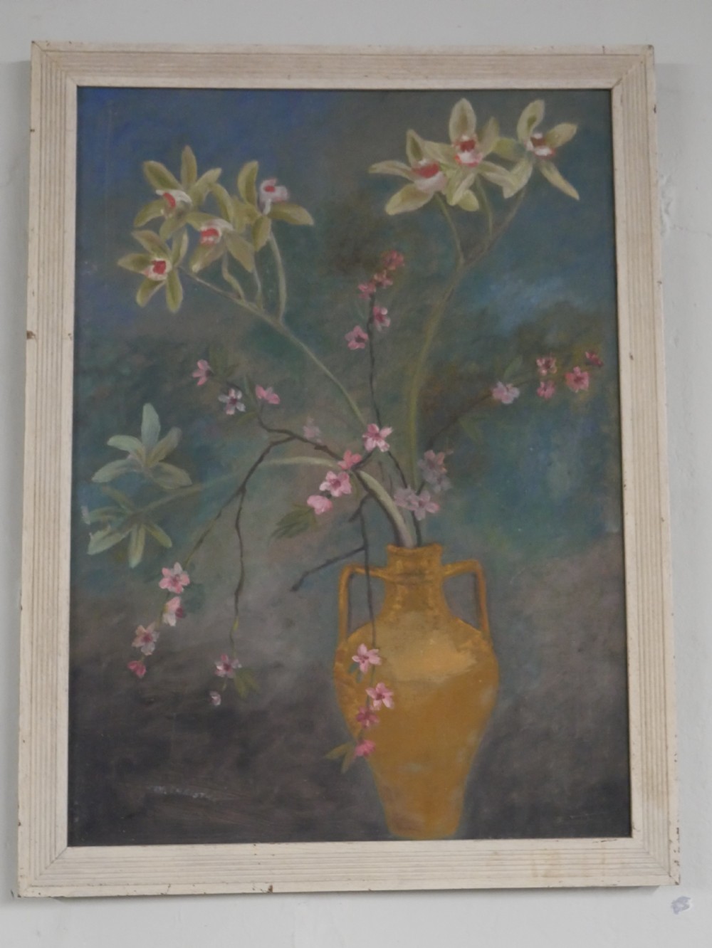 A 1960s framed floral still life painting depicting green orchids and pink blossoms in a yellow two-handled vase against a dark blue background. View X