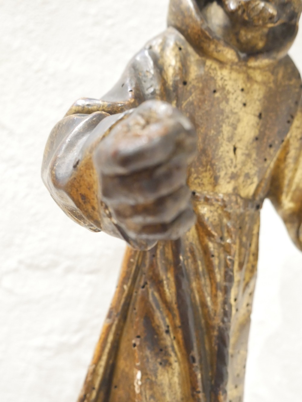 A carved giltwood figure depicting Saint Francis in draped monastic robes standing on a dark wooden plinth. View VIII