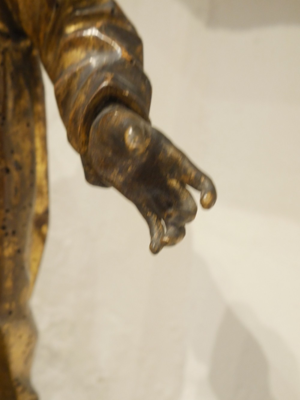 A carved giltwood figure depicting Saint Francis in draped monastic robes standing on a dark wooden plinth. View IX