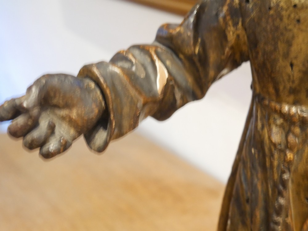 A carved giltwood figure depicting Saint Francis in draped monastic robes standing on a dark wooden plinth. View XIII