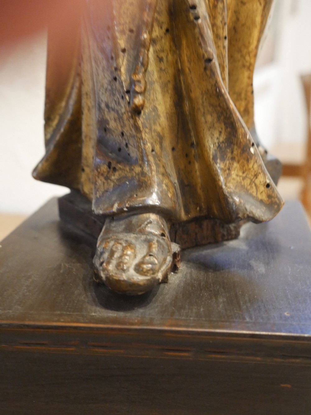 A carved giltwood figure depicting Saint Francis in draped monastic robes standing on a dark wooden plinth. View XV