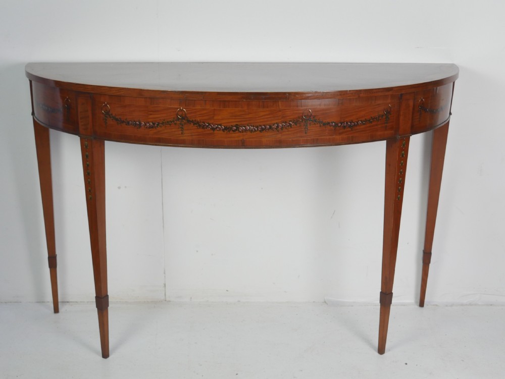 An English 19th-century demilune console table with hand-painted floral swags across the curved apron and slender tapered square legs.