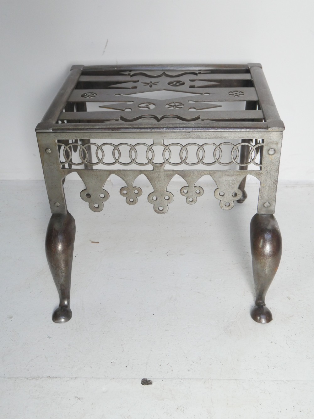 An antique pierced steel hearth footman featuring cabriole front legs, pad feet, and a fretted top. View II