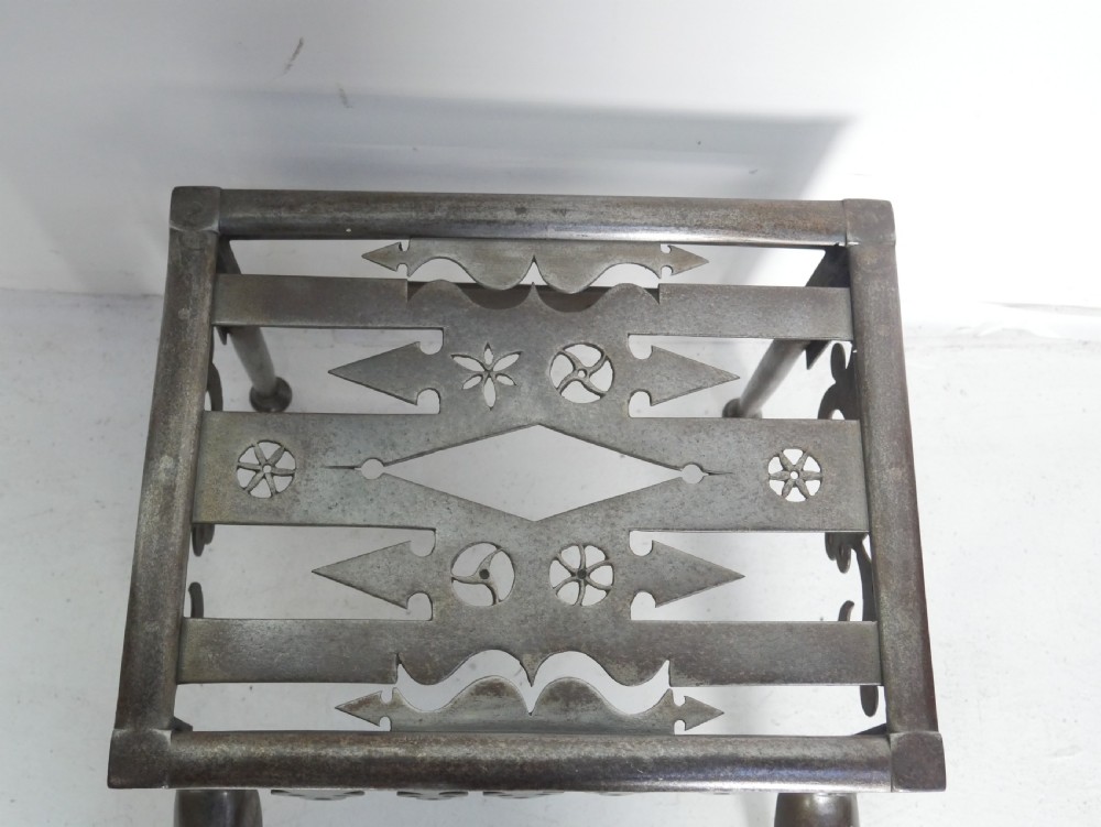 An antique pierced steel hearth footman featuring cabriole front legs, pad feet, and a fretted top. View III