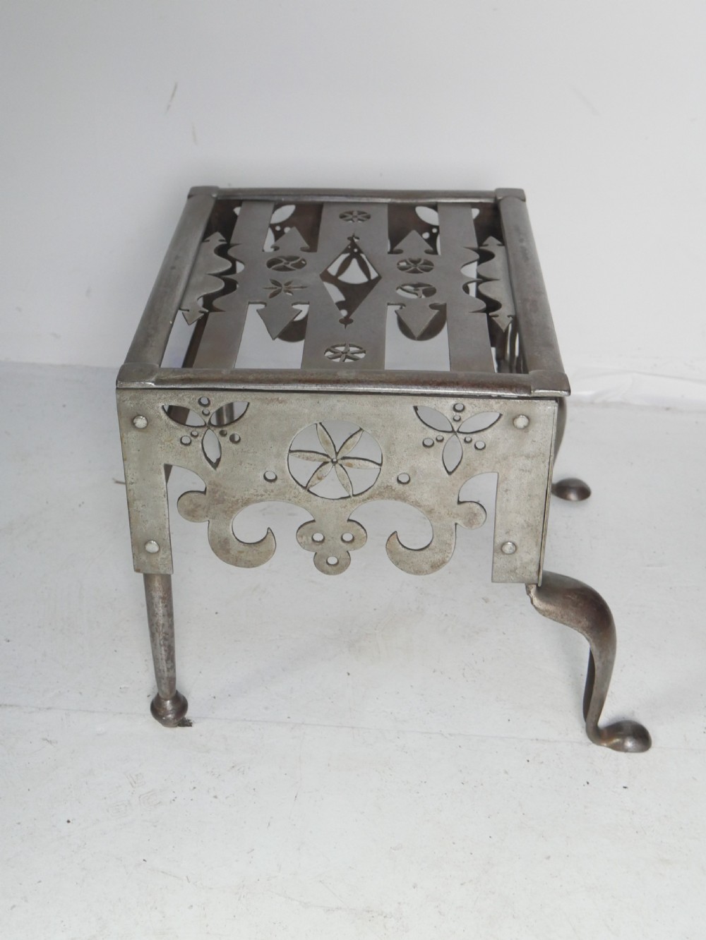 An antique pierced steel hearth footman featuring cabriole front legs, pad feet, and a fretted top. View VII