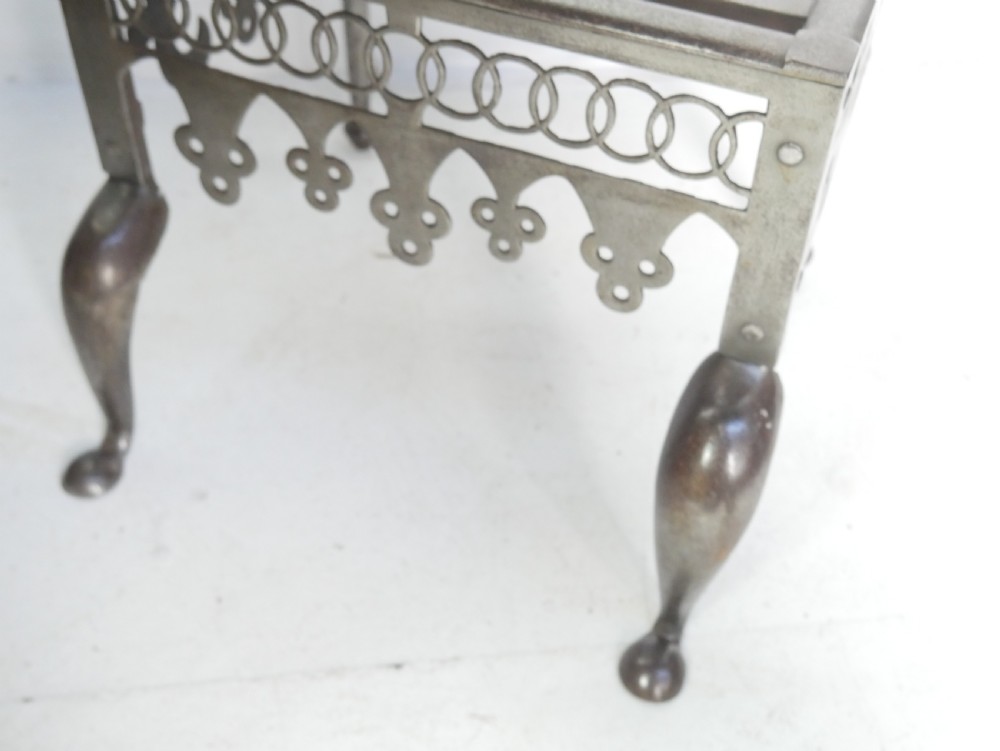 An antique pierced steel hearth footman featuring cabriole front legs, pad feet, and a fretted top. View X
