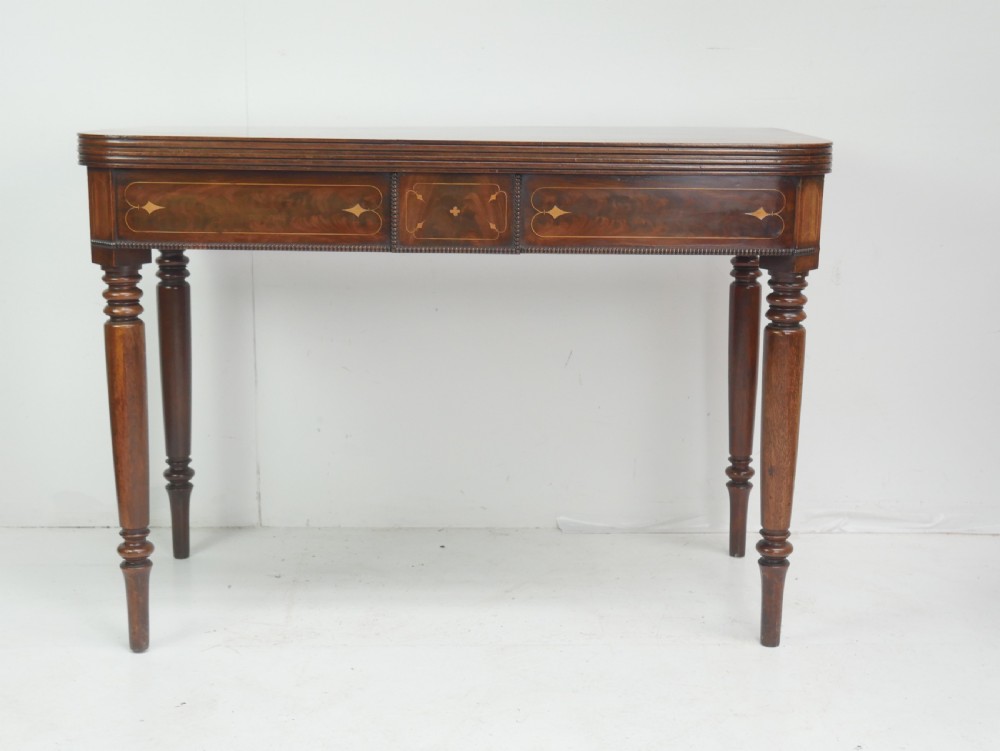 A Regency mahogany fold-over side table with an inlaid decorative frieze and four turned legs.