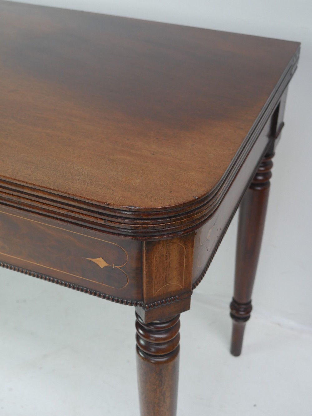 A Regency mahogany fold-over side table with an inlaid decorative frieze and four turned legs. View III