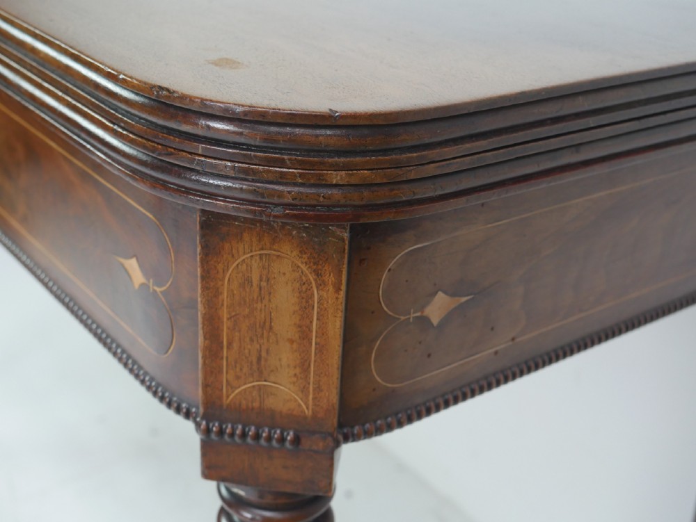 A Regency mahogany fold-over side table with an inlaid decorative frieze and four turned legs. View V