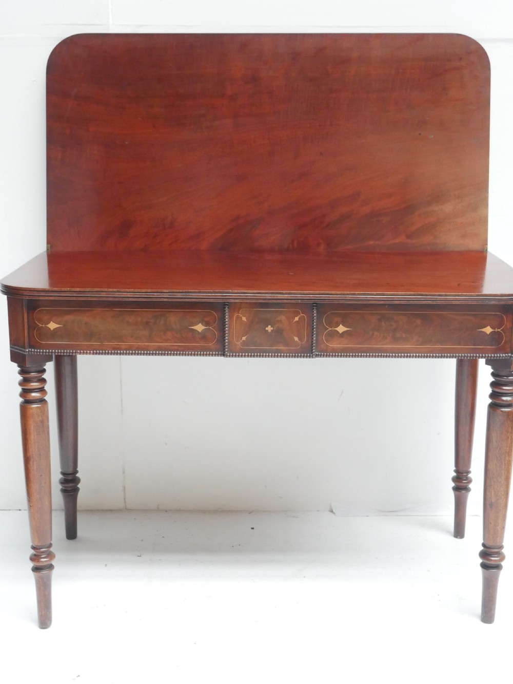 A Regency mahogany fold-over side table with an inlaid decorative frieze and four turned legs. View VII