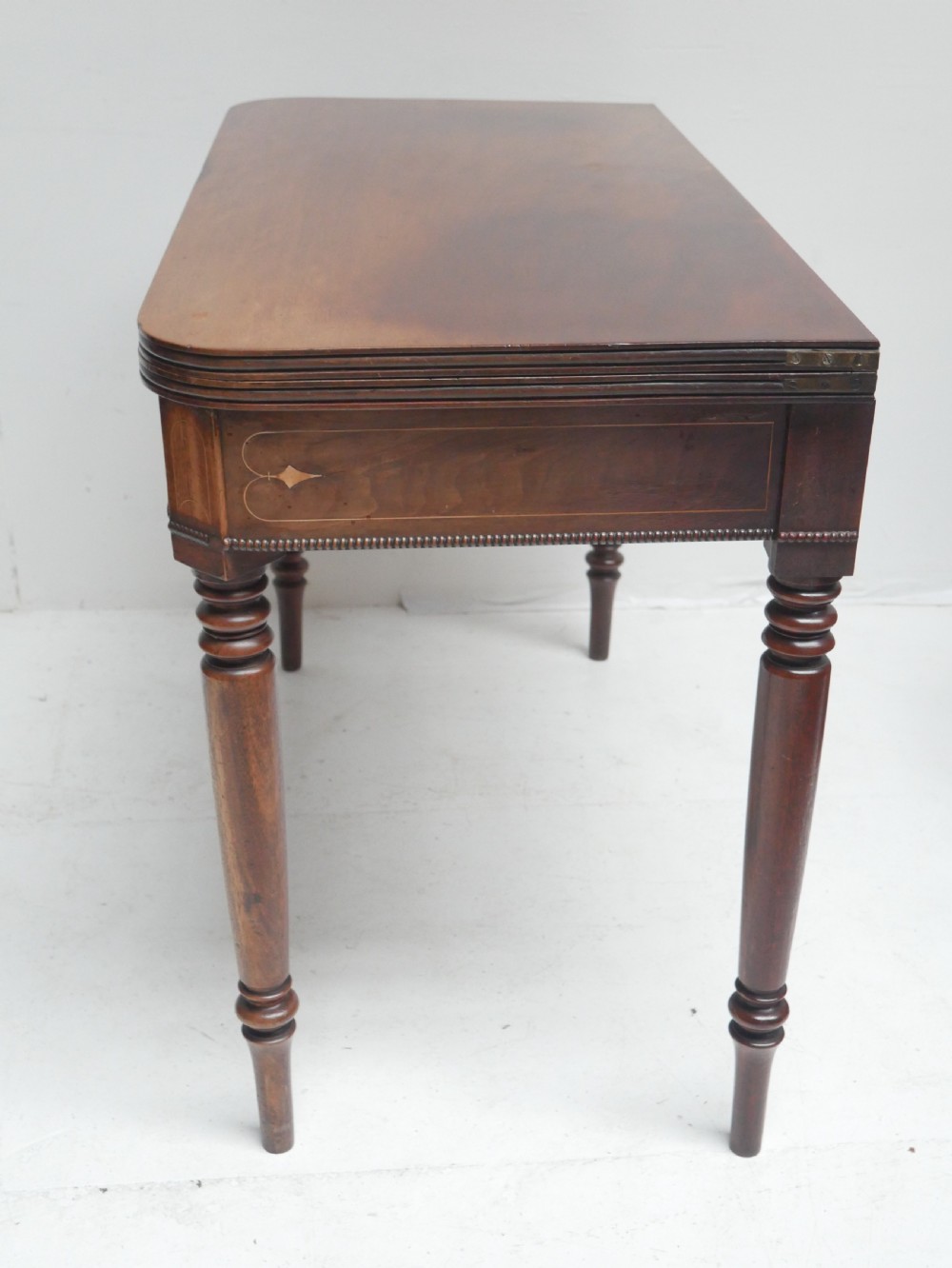 A Regency mahogany fold-over side table with an inlaid decorative frieze and four turned legs. View VIII