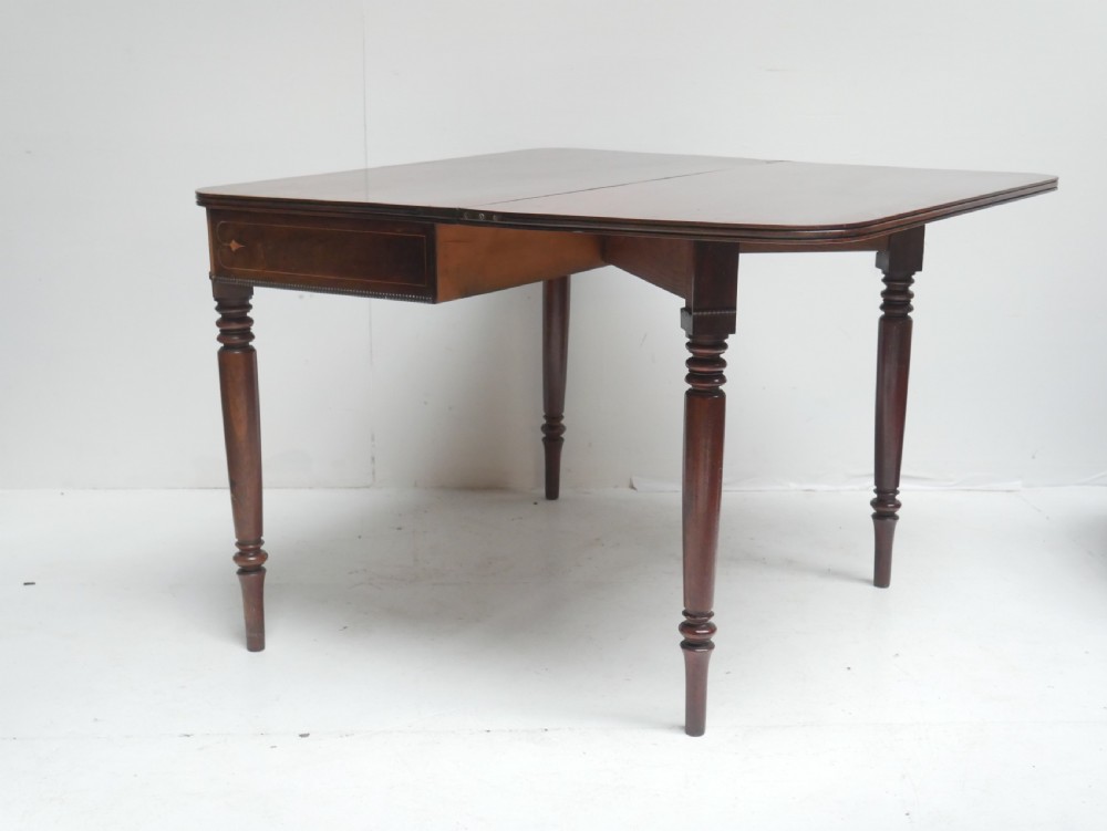 A Regency mahogany fold-over side table with an inlaid decorative frieze and four turned legs. View X