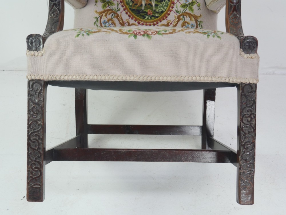 A Georgian Gainsborough armchair with dark carved mahogany legs, upholstered in beige needlepoint tapestry featuring a central pastoral scene and floral borders. View VII
