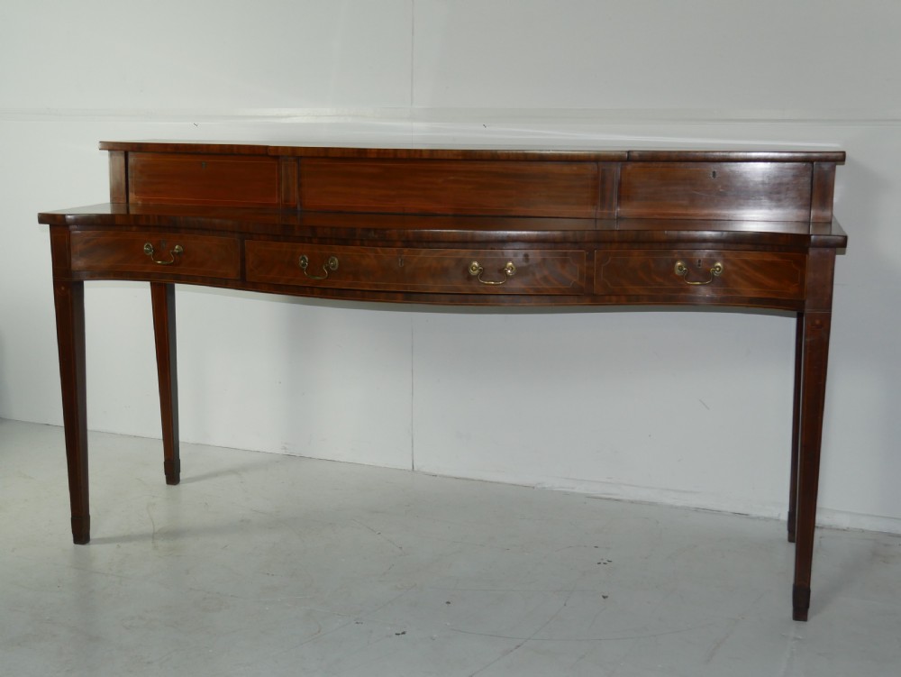 A Scottish Georgian mahogany sideboard featuring a raised stage top superstructure, stringing inlay, three drawer fronts with brass drop handles, and square tapered legs. View II
