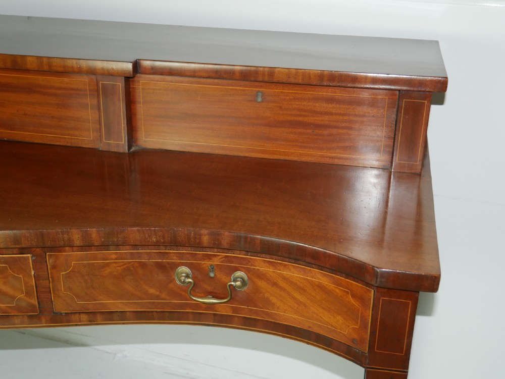 A Scottish Georgian mahogany sideboard featuring a raised stage top superstructure, stringing inlay, three drawer fronts with brass drop handles, and square tapered legs. View VIII