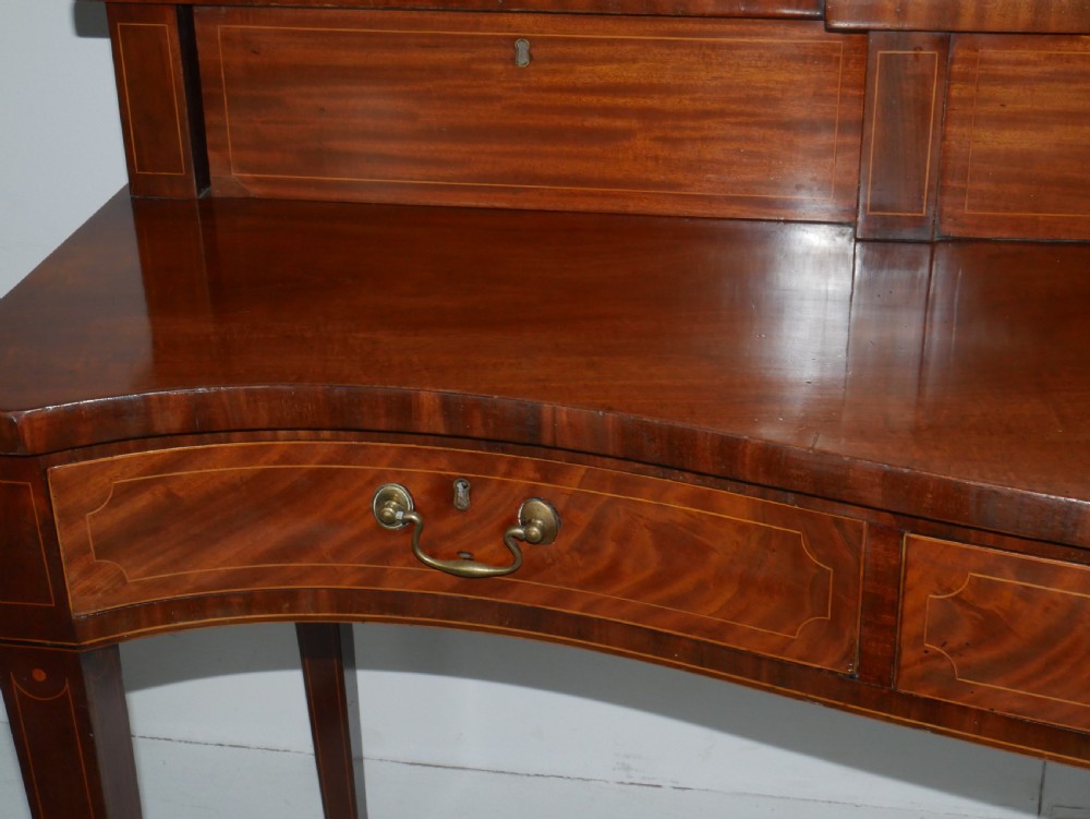 A Scottish Georgian mahogany sideboard featuring a raised stage top superstructure, stringing inlay, three drawer fronts with brass drop handles, and square tapered legs. View IX