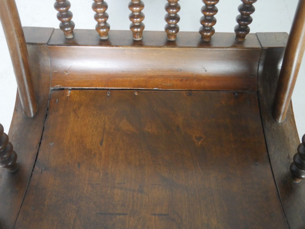 An antique warm brown wooden rocking chair featuring intricate bobbin-turned spindles along the backrest, armrests, legs, and stretchers. View VIII