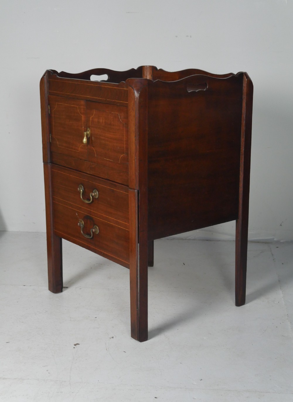 A Georgian mahogany bedside cabinet featuring a tray top gallery, two cupboard doors with string inlay, and two drawers with brass swan-neck handles. View II