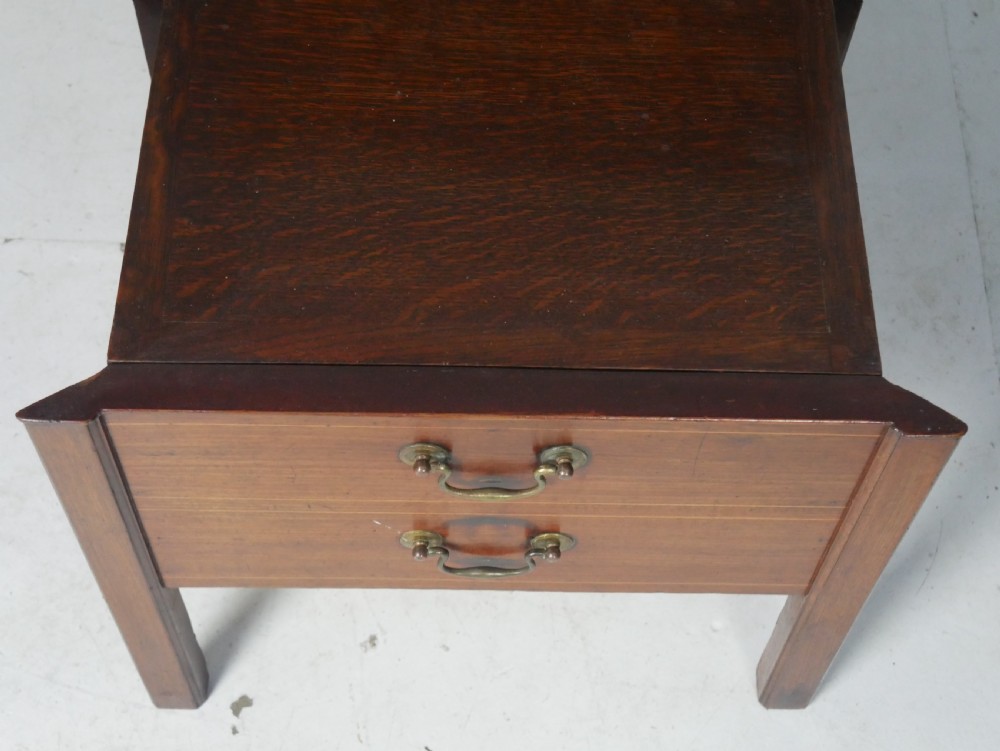 A Georgian mahogany bedside cabinet featuring a tray top gallery, two cupboard doors with string inlay, and two drawers with brass swan-neck handles. View VII