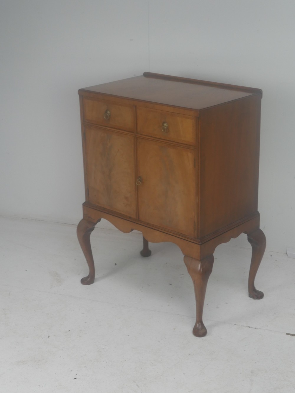 A Queen Anne revival walnut bedside cabinet featuring two top drawers, a two-door cupboard, and tall cabriole legs. View II