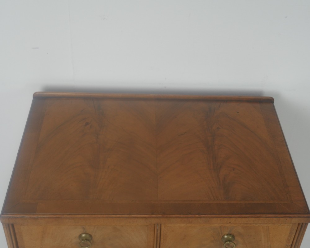 A Queen Anne revival walnut bedside cabinet featuring two top drawers, a two-door cupboard, and tall cabriole legs. View III