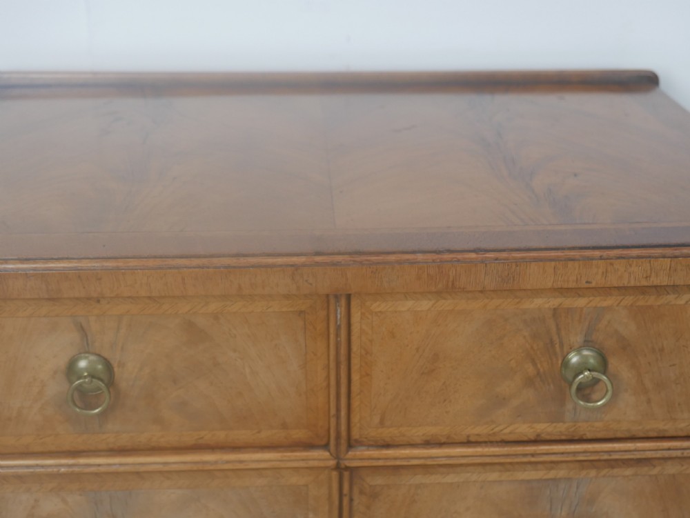 A Queen Anne revival walnut bedside cabinet featuring two top drawers, a two-door cupboard, and tall cabriole legs. View V